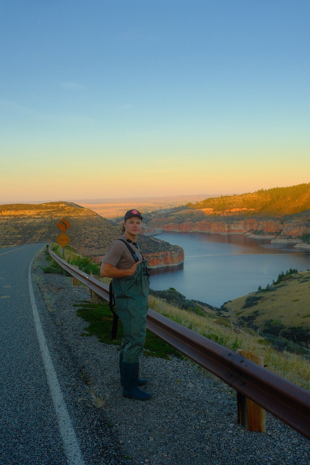 Dawson Hering in waders on a roadside overlooking a canyon lake at sunset